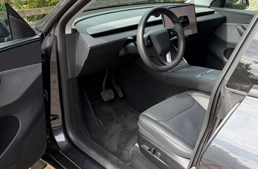 Tesla Model Y 2025 — førerplads med rat og betjeningsskærm